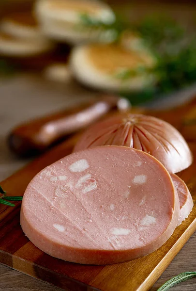 slices of Bologna IGP mortadella on a rustic wooden cutting board and Modenese tigelle