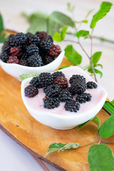 Wild berries naturally on a wooden cutting board with creamy yogurt