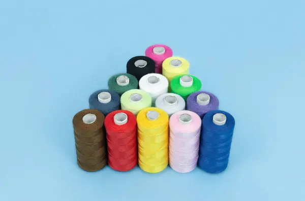 Various spools of sewing cotton thread of different colors on colored background