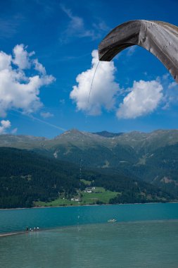 Curon Venosta, Italy - August 12, 2024 :view of Resia lake park  where you can admire the famous bell tower of the submerged church emerging from the water. clipart