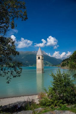 View of Lake Resia - Italy where you can admire the famous bell tower of the submerged church emerging from the water. clipart