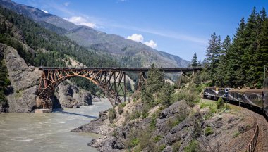 Rocky Dağları lüks treni 2 Haziran 2023 'te Kanada' da Rocky Dağları 'ndaki Fraser Nehri boyunca demir köprüye yaklaşıyor.