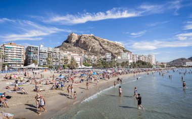 Alicante beach  packed with sun bathers, and Santa Barbara castle in Alicante, Spain on 29 August 2023 clipart