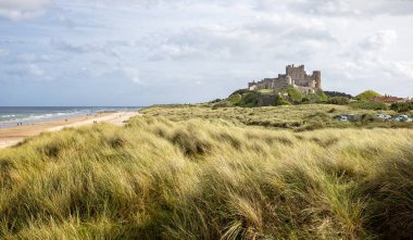 Bamburgh Kalesi 'nin batısından kıyı manzarası 25 Eylül 2023' te Bamburgh, Northumberland, İngiltere 'deki kum tepelerinden yükseliyor.