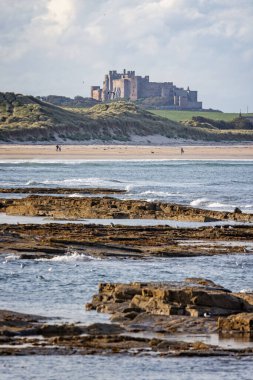 26 Eylül 2023 'te İngiltere' nin Northumberland kentindeki deniz kenarındaki kum tepelerinden yükselen Bamburgh Kalesi 'nin kıyı manzarası.