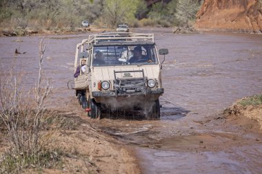 Pinzgauer off road vehicle splashing through meltwater river on tour of the canyon floor of Canyon de Chelly National Monument in Arizona, USA on 19 April 2024 clipart