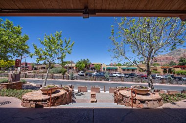 1 Mayıs 2024 'te Sedona, Arizona, ABD' de 89A otobanındaki dükkanlar ve arabalar arka planda kırmızı kaya izmaritleri.