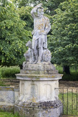 16 Haziran 2024 'te Suffolk, İngiltere' deki Somerleyton Hall 'da köpeklerle dolu taş bir avcı heykeli.