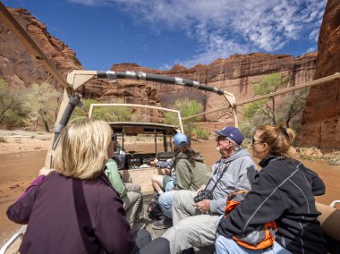 Tourists on board 6wd tour along flooded river at bottom of Canyon de Chelley, Arizona, USA on 19 April 2024 clipart