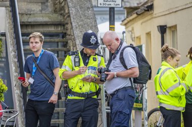Genç polis ve fotoğrafçı, İngiltere Bisiklet Turu sırasında 12 Eylül 2014 'te Avon, Wiltshire, İngiltere' de Bradford 'dan geçerken kamera ekranında fotoğrafları birlikte izliyorlar.