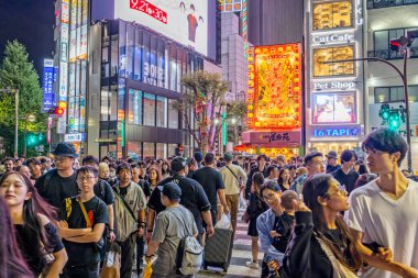 Crowds of people crossing street at night amidst bright neon lights in Shinjuku, Tokyo, Japan on 23 September 2023 clipart