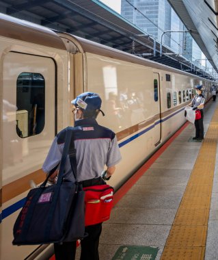 Tokyo İstasyonu 'ndaki Shinkensen platformunda 7 Ekim 2024' te Japon mermi trenine binip temizlenmeyi bekleyen temizlikçiler var.