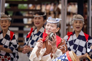 Close up of elderly Japanese woman iperfoming in traditional japanese dance in Kimono playing small gong - at the Senso-Ji Temple in Tokyo, japan on 6 October 2024 clipart