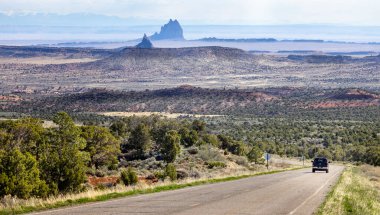 Black truck driving down deserted highway with dramatic landscape of red sandstone Mesas and Buttes, near Red valley, Arizona, USA on 20 April 2024 clipart