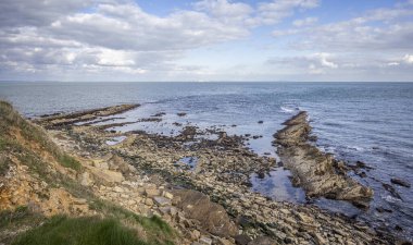 View from Peveril Point to the Isle of Wight on the horizon with rocky outcrops at low tide in Swanage, Dorset, UK on 13 March 2025