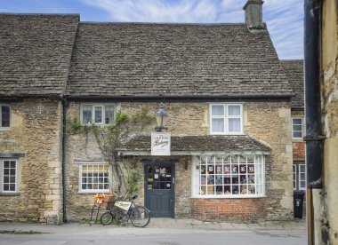 Lacock pastanesinin önünde 25 Mart 2025 'te Lacock, Wiltshire, İngiltere' deki Church caddesinde antika dağıtım bisikleti var.