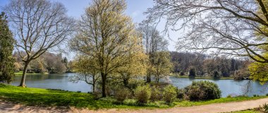 Stourhead Gölü 'nün panoramik manzarası ve köprüye doğru akrooları ve Stourhead, Wiltshire, İngiltere' deki Apollo Tapınağı 'nı 5 Nisan 2025' de gösteriyor.
