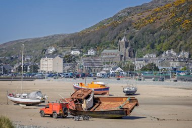 9 Nisan 2025 'te Galler' de, St Johns Kilisesi 'nin arkasında, Barmouth limanındaki alçak gelgitte RNLI cankurtaran botu da dahil olmak üzere kara botları.