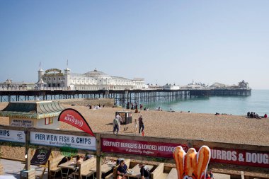 Brighton Palace Rıhtımı ve plajı 27 Nisan 2025 'te Brighton, Sussex, İngiltere' de güneşlenenlerle sıcak bir nisan günü.