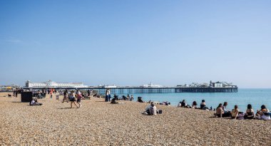 Brighton Palace Rıhtımı ve plajı 27 Nisan 2025 'te Brighton, Sussex, İngiltere plajında güneşlenenlerle dolu.
