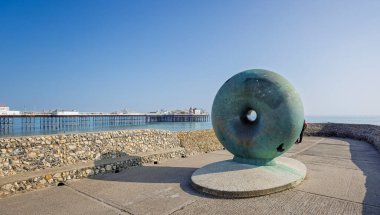 Brighton, Sussex, İngiltere 'de Brighton Palace İskelesi yakınlarında 27 Nisan 2025' te, Groyne 'da yüzen bronz çörek şeklinde büyük bir heykel.