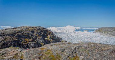 Ilulissat, 17 Temmuz 2022 'de Grönland' ın Ilulissat kentinde turistlere ölçek duygusu veren buzul heykeli.