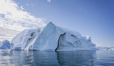 Grönland 'daki Disko Körfezi' nde derin yarık ve dramatik gökyüzüne sahip büyük bir buzdağı.