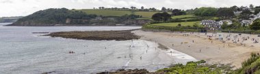 31 Mayıs 2025 'te Falmouth, Cornwall, İngiltere' de güneş banyosu ve yüzücülerle dolu Gyllyngvase Plajı panoramik manzarası