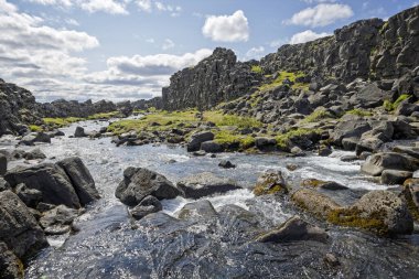 Şelaleden akan su, 9 Haziran 2025 'te İzlanda' daki Thingvellir Ulusal Parkı 'ndaki tektonik plakalar arasındaki yarık vadisinde akıyor.