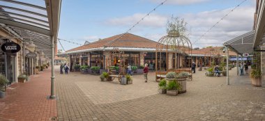 2 Ekim 2025 'te Clark Village alışveriş merkezinin merkezindeki dükkan, restoran ve açık hava oturma alanının panoramik manzarası, Street, Somerset, İngiltere