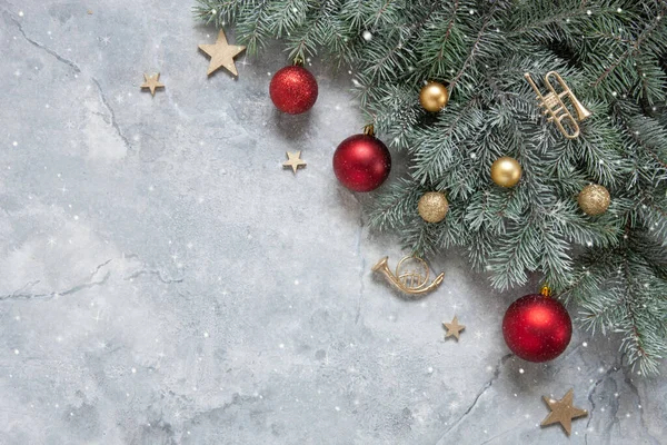雪のモミの木の枝 おもちゃのトランペット 大理石の背景に赤と金色のクリスマスボールとクリスマスと新年のお祝いの組成 — ストック写真
