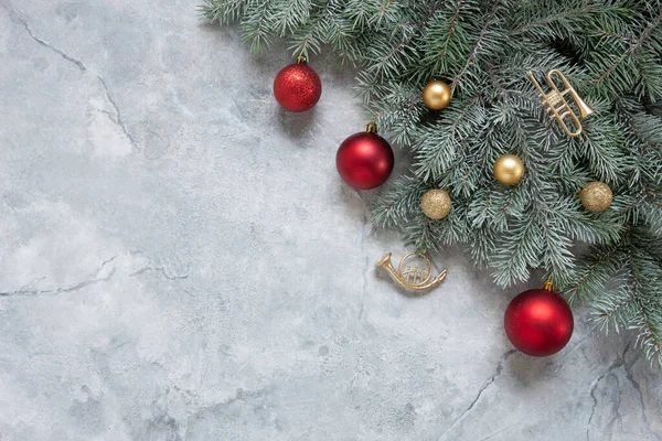 雪のモミの木の枝 おもちゃのトランペット 大理石の背景に赤と金色のクリスマスボールとクリスマスと新年のお祝いの組成 — ストック写真