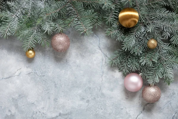 雪のモミの木の枝 穏やかなピンクと大理石の背景に黄金のクリスマスボールとクリスマスと新年のお祝いの組成 — ストック写真