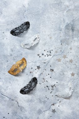 Karnaval maskeleri ve gümüş parıltılı konfetiler. Üst görünüm, mermer arkaplanı kapat