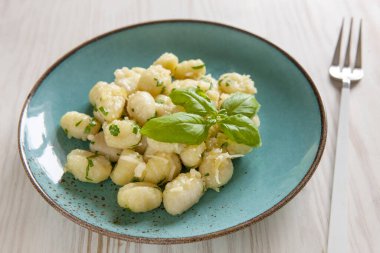 Traditional homemade cooked italian potato gnocchi with butter, parsley and parmesan cheese on white wooden background