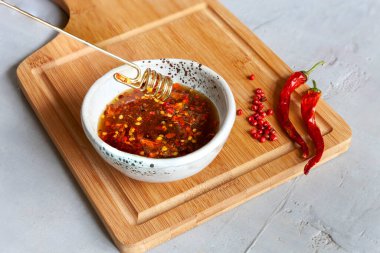 Spicy or hot chilli honey in the bowl on the wooden kitchen board clipart