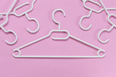 Pembe arka planda beyaz plastik askılar. Satış, dükkan, ikinci el, çevrimiçi ticaret, marka satış platformu