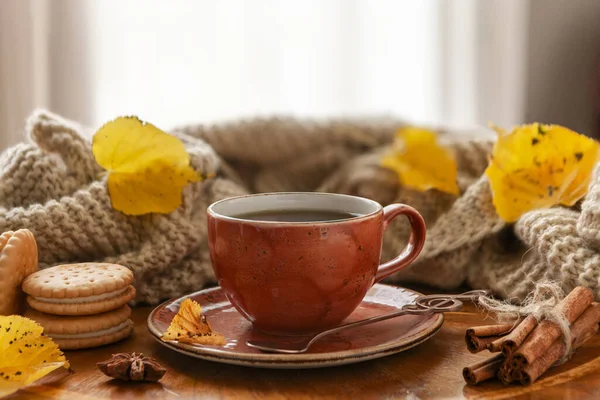 Cozy autumn photo with a cup of coffee with crispy homemade cookies and cinnamon on the background of warm plaid, scarf