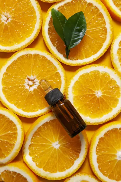 stock image Orange organic aromatic oil in a glass bottle with a pipette on a background of fresh orange slices