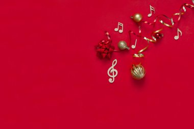 Ahşap notalar ve Noel süslemeleriyle süslü kırmızı bir Noel ve yeni yıl arkaplanı. Üst görünüm, kopyala boşluk, düz la