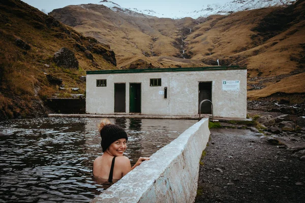 Geothermal pools on a farm in Iceland, surrounded by mountains and snow. Seljavellir South Iceland.