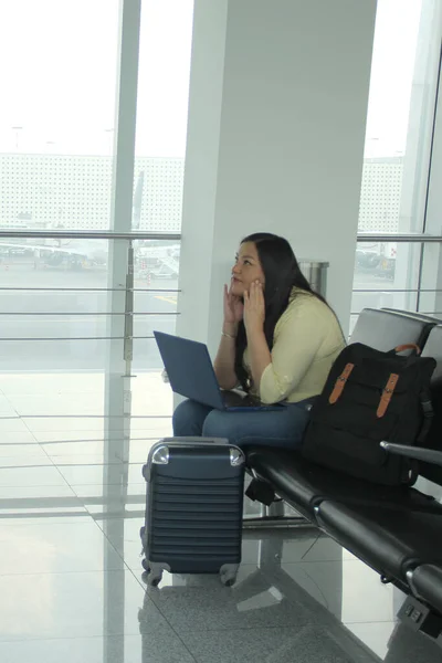 여성은 비행기를 기다리는 대기실에서 옆에서 노트북을 가지고 일하고 — 스톡 사진