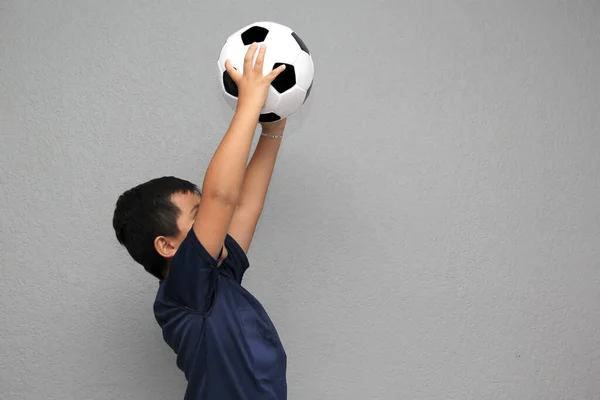 Hispanic Latino 8-year-old boy plays with a soccer ball very excited that he is going to see the football game and wants to see his team win