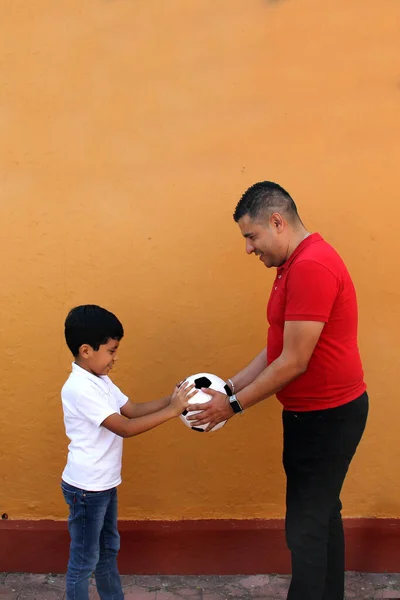 stock image Latino dad and son share their love for soccer, they take a ball with their hands excited to watch the football game