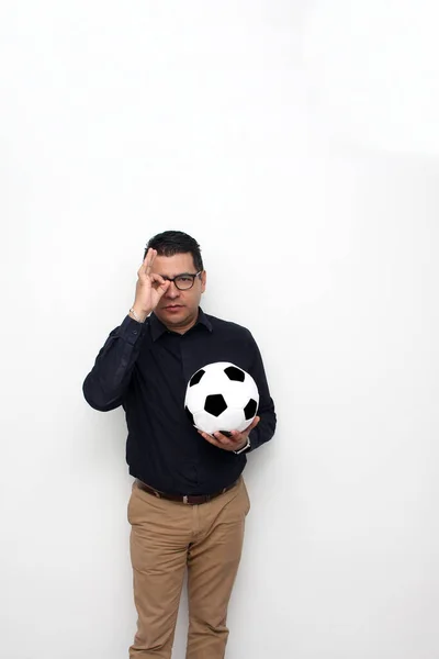 Latino adult office man plays with a soccer ball very excited that he is going to see the game and wants to see his team win