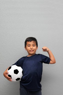 Latin kökenli 8 yaşındaki çocuk futbol topuyla oynuyor. Futbol maçını izleyeceği için çok heyecanlı ve takımının kazandığını görmek istiyor.