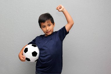 Latin kökenli 8 yaşındaki çocuk futbol topuyla oynuyor. Futbol maçını izleyeceği için çok heyecanlı ve takımının kazandığını görmek istiyor.