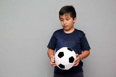 Latin kökenli 8 yaşındaki çocuk futbol topuyla oynuyor. Futbol maçını izleyeceği için çok heyecanlı ve takımının kazandığını görmek istiyor.
