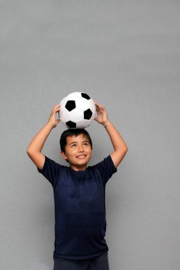 Latin kökenli 8 yaşındaki çocuk futbol topuyla oynuyor. Futbol maçını izleyeceği için çok heyecanlı ve takımının kazandığını görmek istiyor.