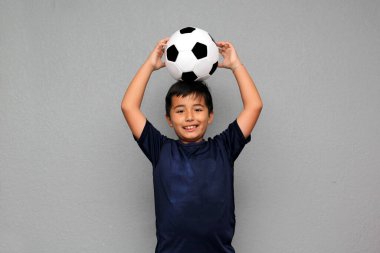 Latin kökenli 8 yaşındaki çocuk futbol topuyla oynuyor. Futbol maçını izleyeceği için çok heyecanlı ve takımının kazandığını görmek istiyor.